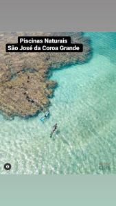 a person swimming in the water in the ocean at Casa 3quartos rota Maragogi Carneiros in São José da Coroa Grande