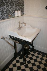 a white sink in a bathroom with a checkered floor at Historische Pension Villa Uhlenhorst in Wernigerode