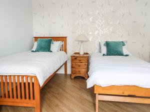 two twin beds in a room with a night stand at Castlebrae in Jedburgh