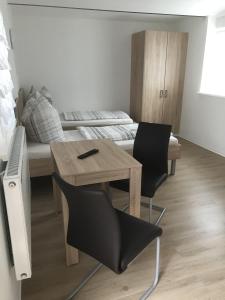 Cette chambre comprend une table, des chaises et un lit. dans l'établissement Pension Kaiser, à Haldensleben