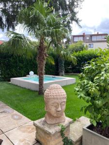 a statue of a head in a garden with a pool at Apartment am Weinberg in Deidesheim