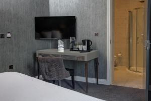 a hotel room with a tv and a chair at The Eccleston Hotel; BW Signature Collection in Saint Helens