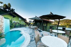 a patio with tables and chairs and a swimming pool at Pousada Vila do Bosque in Bombinhas