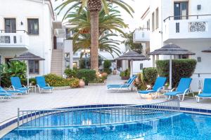 a swimming pool with blue chairs and palm trees at Flamingos Hotel Apartments in Kato Daratso