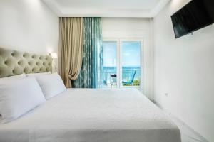 a bedroom with a white bed and a window at Beach Front Casa Elena in Hanioti