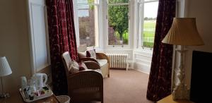 a living room with a large window and chairs at Arden House - rooms with continental breakfast in Musselburgh