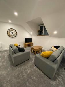 una sala de estar con 2 sofás y un reloj en la pared en Crows Nest en Par