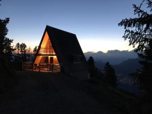 a house on top of a hill with the sun setting at Chalet Biancaneve - Alpe Cermis Cavalese in Cavalese