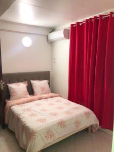 - une chambre avec un lit et des rideaux rouges dans l'établissement Maison charmante à Pointe-Noire avec vue mer, à Pointe-Noire