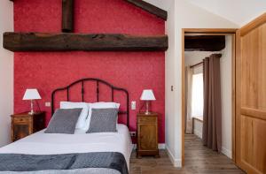 Un dormitorio con una pared roja y una cama en LE COTTAGE DU PARC, en Chambéon