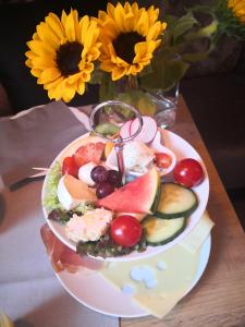 ein Teller mit Essen auf einem Tisch neben einer Vase mit Blumen in der Unterkunft Hotel garni Haus am Meer in Neuharlingersiel