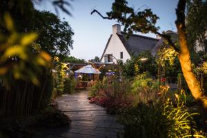 a garden path leading to a house with lights at La Mare aux Oiseaux, The Originals Collection in Saint-Joachim