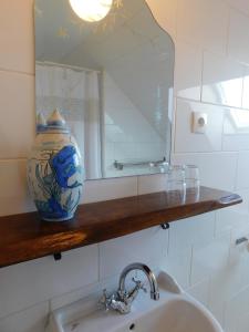 a bathroom with a sink and a mirror and a vase at La Maison du Cerf in Urciers