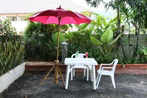 ラマイにあるBT マンションのテーブルと椅子2脚、赤い傘