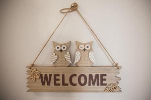 three owls sitting on a sign with a welcome sign at Rooms Klik Postojna in Postojna
