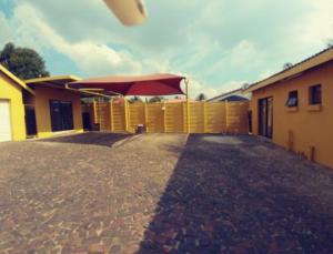 un patio con una sombrilla roja y una valla en The Loft Lynette's en Krugersdorp