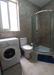a bathroom with a toilet and a shower and a washing machine at F10 Modern and Bright Apartment in Malta in Msida