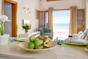 a table with a bowl of fruit on a table with the beach at Casita Martina in Punta Mujeres