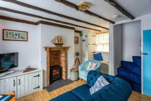a living room with a blue couch and a fireplace at Smuggler's Cottage Broadstairs in Broadstairs
