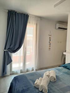 una camera da letto con un letto, asciugamani e una finestra di DAMASTE' CASA VACANZE PACHINO a Pachino