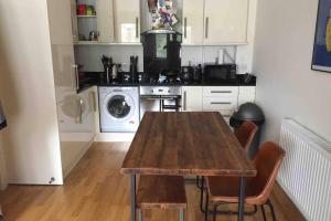 a kitchen with a wooden table with chairs and a washing machine at Charming flat in Golders Green with parking space in London