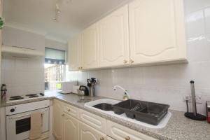 a kitchen with white cabinets and a sink at 43C Medmerry Park 2 Bedroom Chalet in Earnley