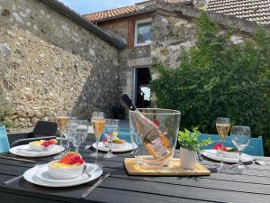 una mesa de madera con comida y copas de vino. en La Grange d' Angel, en Châtillon-sur-Marne