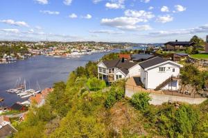 a house on a hill next to a body of water at Apartment with amazing views - free parking in Arendal