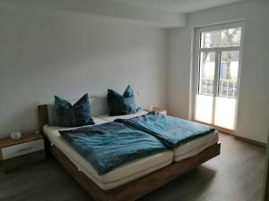 una camera da letto con un letto con lenzuola blu e una finestra di Ferienwohnung am Schloßpark a Bad Berleburg