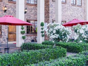two red umbrellas in front of a building at Alveston Manor Hotel in Middelburg