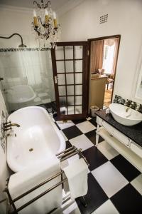 een badkamer met een wit bad en een wastafel bij Godiva Spa & Guesthouse in Groblersdal