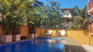 einen Pool mit Stühlen neben einem Gebäude in der Unterkunft Ventura - Apto com piscina, vista mar, churrasqueira privativa, ar con, wi-fi, netflix, garagem in Paraty