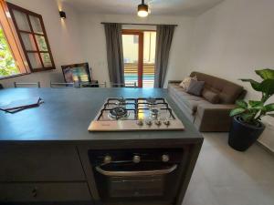 cocina con fogones y sala de estar. en Catimbau - Flat com Piscina, 50mt da praia, churrasqueira privativa, ar con, wi-fi, netflix, en Paraty 9 fotos más