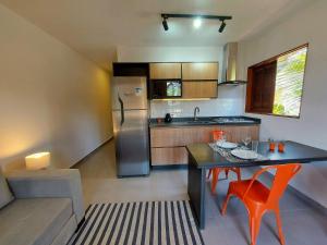 Una cocina con mesa y sillas y un refrigerador. en Cedro - Flat recém inaugurado, 50mts da Praia, Churr, Piscina, WiFi eficiente, Netflix, en Paraty
