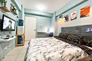 Scandinavian Homey Studio @Green Bay Pluit Apartment في جاكرتا: غرفة نوم بسرير وتلفزيون بشاشة مسطحة