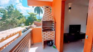 un balcón con una parrilla al aire libre en un lateral de una casa en Algodão - Novo Flat com Piscina, 50mts da praia, churrasqueira privativa, ar con, wi-fi, netflix, garagem, en Paraty