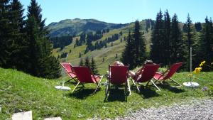 deux personnes assises dans des chaises rouges sur une colline dans l'établissement La Terrasse de Verchaix - Chambre d'hotes et gite, à Verchaix