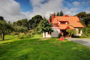 ein Haus mit einem orangenen Dach auf einem grünen Hof in der Unterkunft Pensjonat Alicja in Kosewo