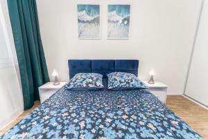 1 dormitorio con 1 cama azul y 2 mesitas de noche en Lily, en Kołobrzeg