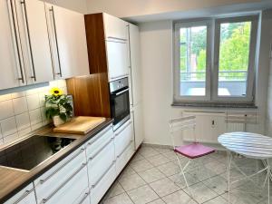 une cuisine avec des placards blancs, une table et une fenêtre dans l'établissement Ferienwohnung Bad Saarow, à Bad Saarow