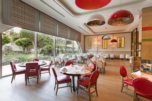 a restaurant with tables and chairs and large windows at Titanic Deluxe Lara in Lara