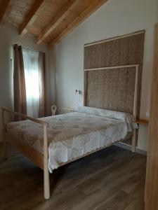 a bedroom with a bed with a wooden headboard at Apartamentos San Juan in Arnuero