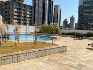 een patio met een zwembad en tafels en gebouwen bij Flat, Savassi Condomínio Century in Belo Horizonte