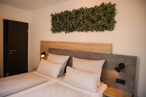 1 cama con almohadas blancas y pared verde en Hotel verWeiler en Fischen