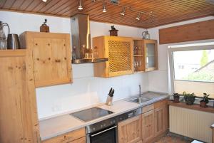 a kitchen with wooden cabinets and a sink and a window at Stilvolles Eifelhaus am Nürburgring mit eigenem Garten in Boos