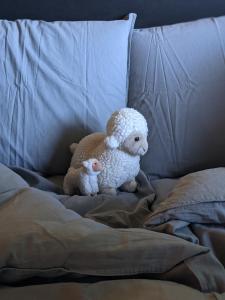 
a white teddy bear sitting on top of a bed at Glempings Jēru Klubs in Promulti
