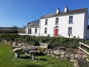 uma casa branca com um banco de pedra à frente. em Abhainn Ri Farmhouse em Blessington