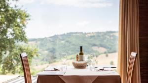 una mesa con una botella de vino y copas en Antico Casale Di Scansano Resort, en Scansano