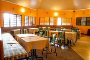un comedor con mesas, sillas y ventanas en Longonot Transit Hotel- Mai Mahiu, en Mai Mahiu