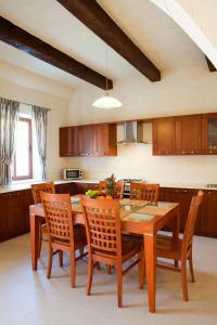 a kitchen with a wooden dining room table and chairs at Girgentina in Xagħra
